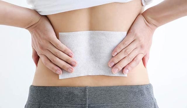 湿布を貼った腰に手をあてる